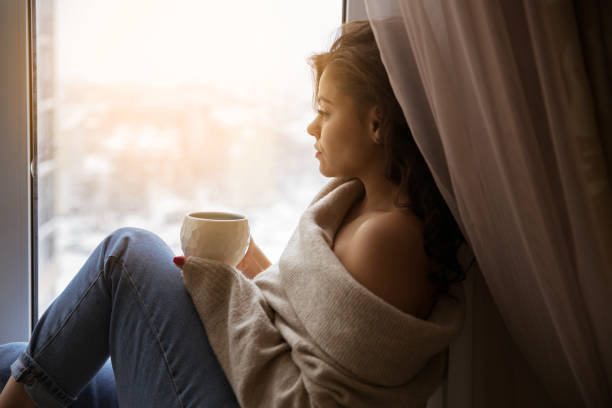 Beautiful girl at the window with a cup of coffee