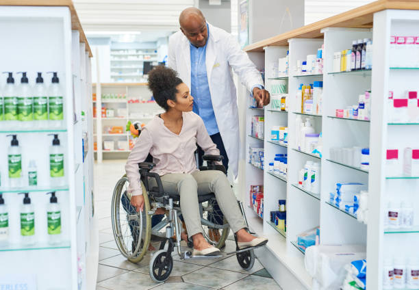 Shot of a pharmacist assisting a young woman with a wheelchair in a chemist